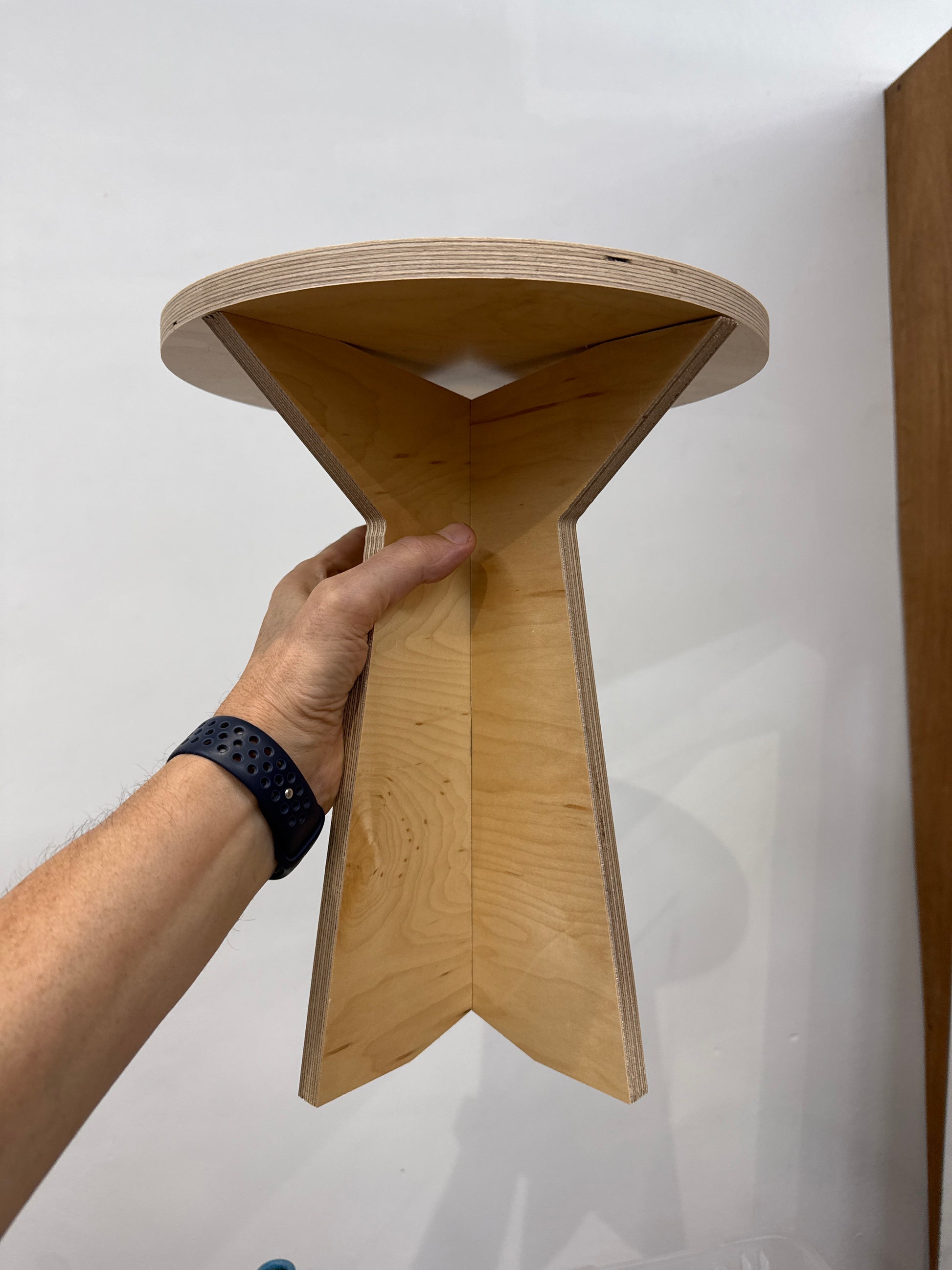 Wooden stool held by a hand on a white background